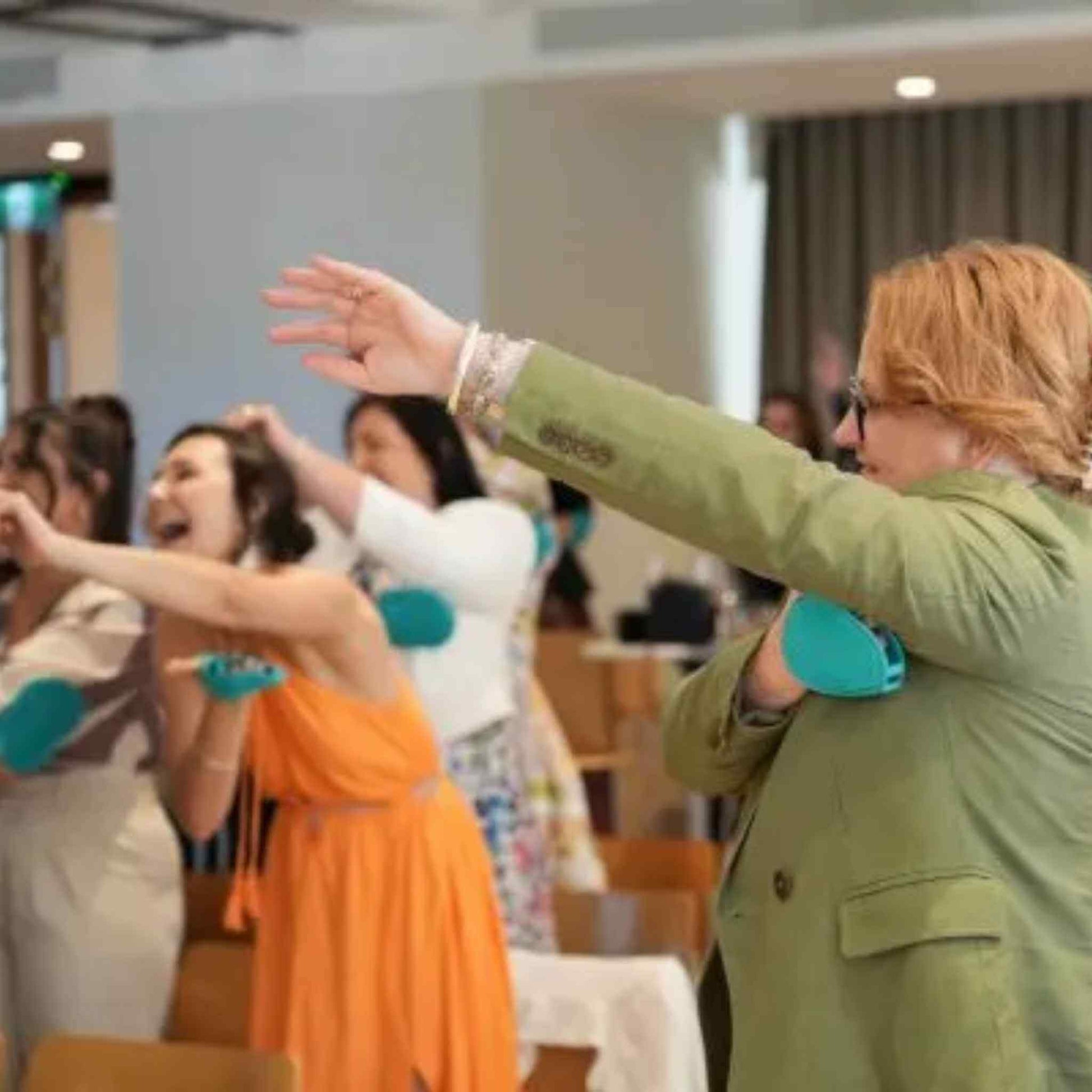 Woman in green coat using the Chelsey Jean Dual Action Lymphatic Gloves in a room with other people.